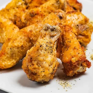 Crispy lemon pepper chicken wings seasoned with black pepper on a white plate at Mo’s in Simsbury.