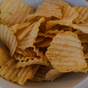 A close-up view of golden, crinkle-cut potato chips in a white serving bowl at Mo's Simsbury location.