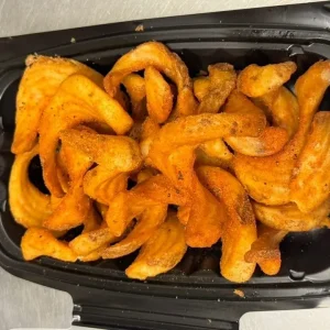 A crispy chicken sandwich topped with cheese sauce and served with curly fries at Mo’s in Simsbury.